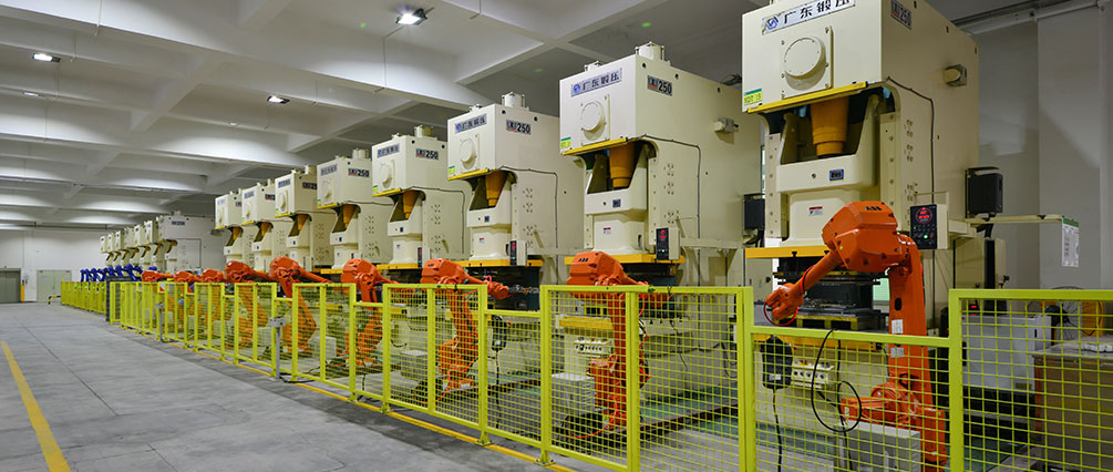 Sheet-metal production line with presses and yellow guarding.